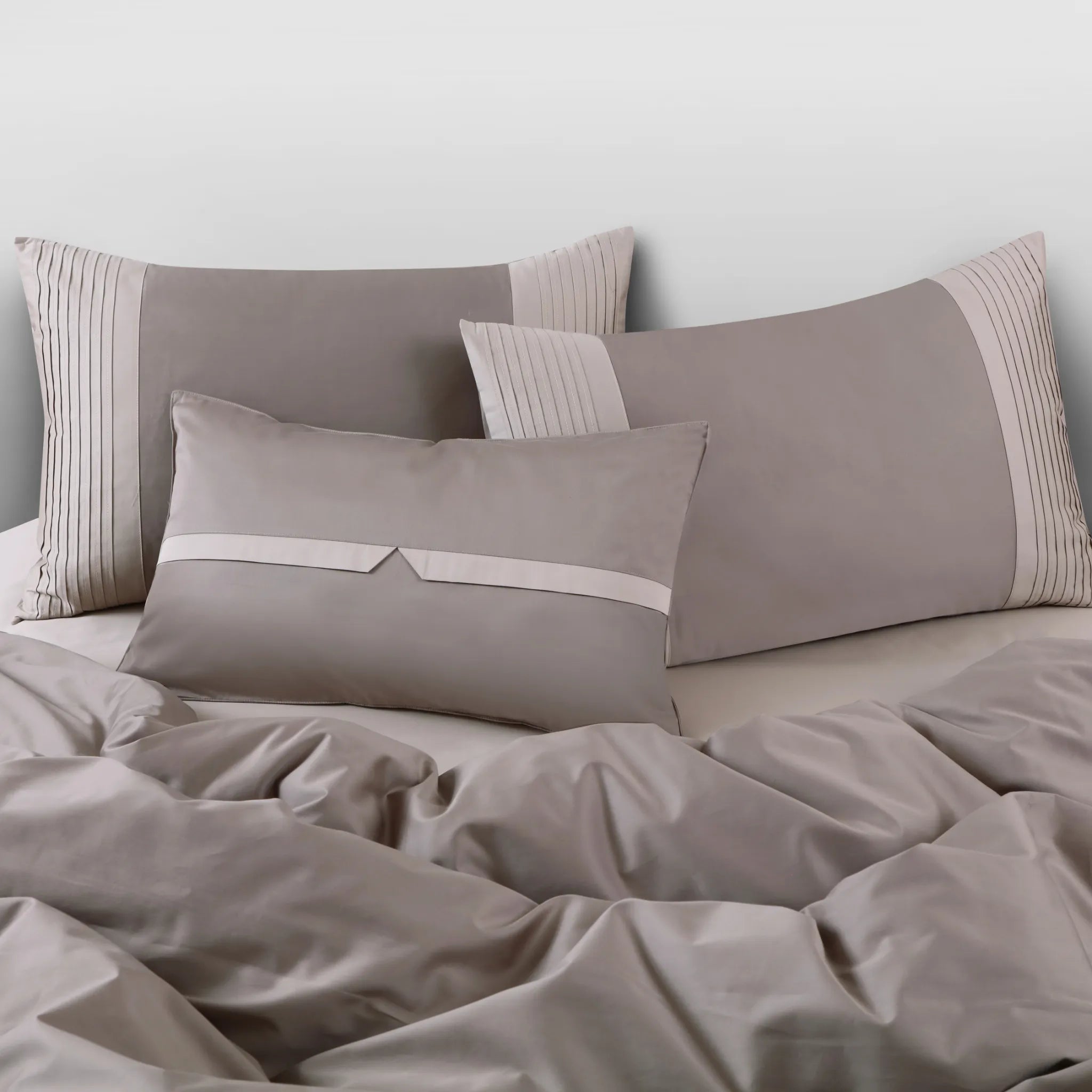 Brown bedding set with pillows on a bed against a light gray wall.