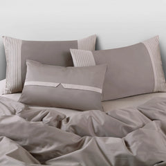 Brown bedding set with pillows on a bed against a light gray wall.
