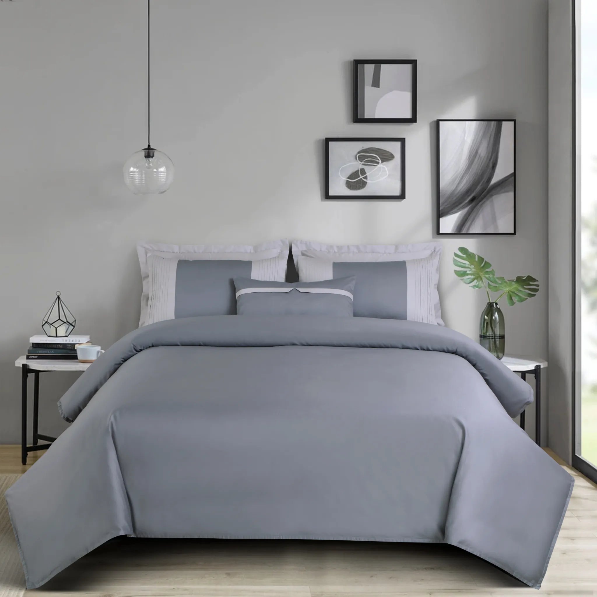 Gray bedding set on a bed in a bedroom with abstract art on the wall.