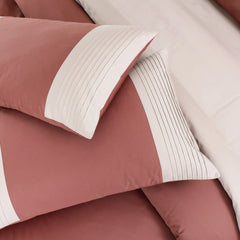 Close-up of pink bedding with white trim on a neutral background