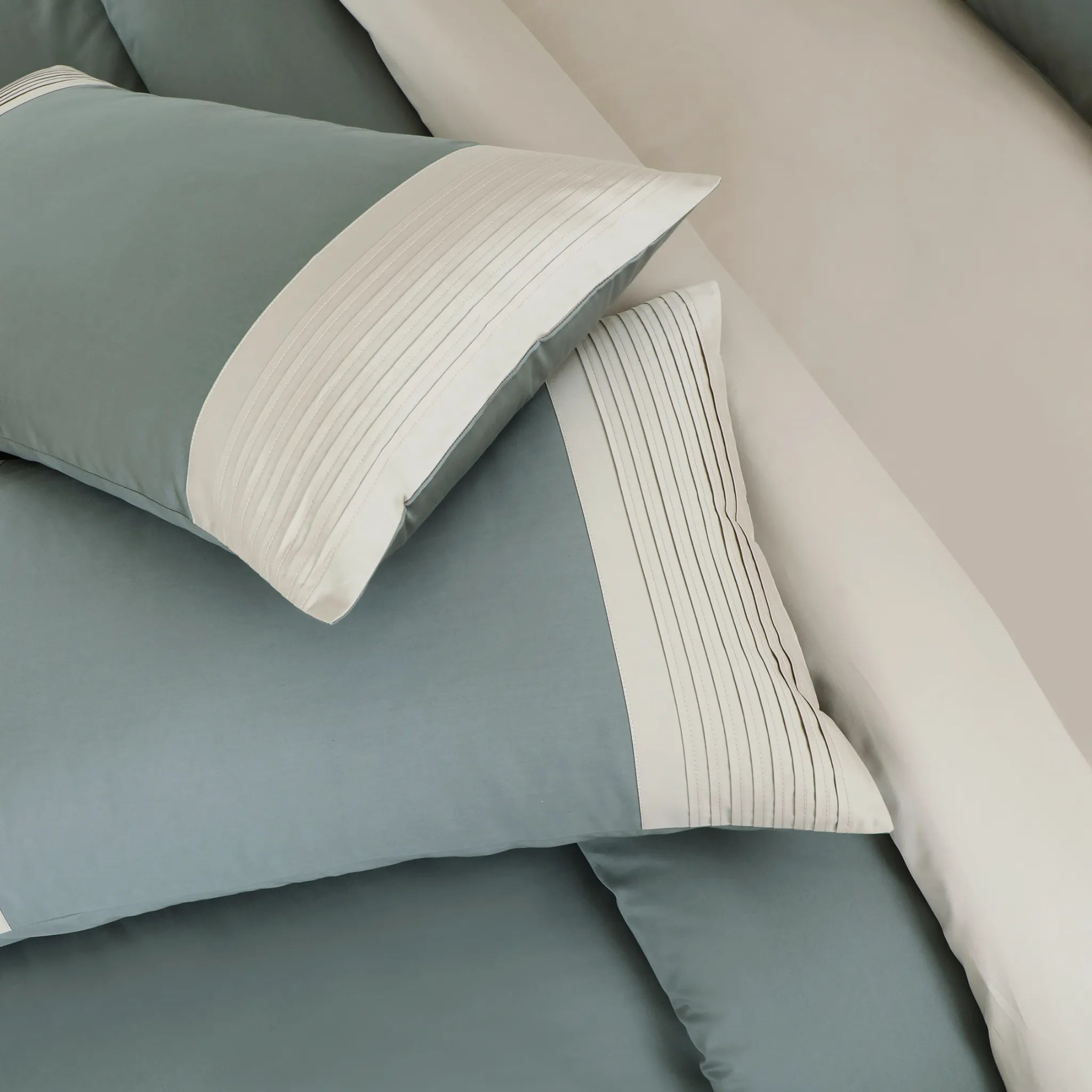 Teal and beige bedding set with pillows on a bed