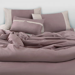 Wine bedding set with matching pillows on a bed against a light blue wall.