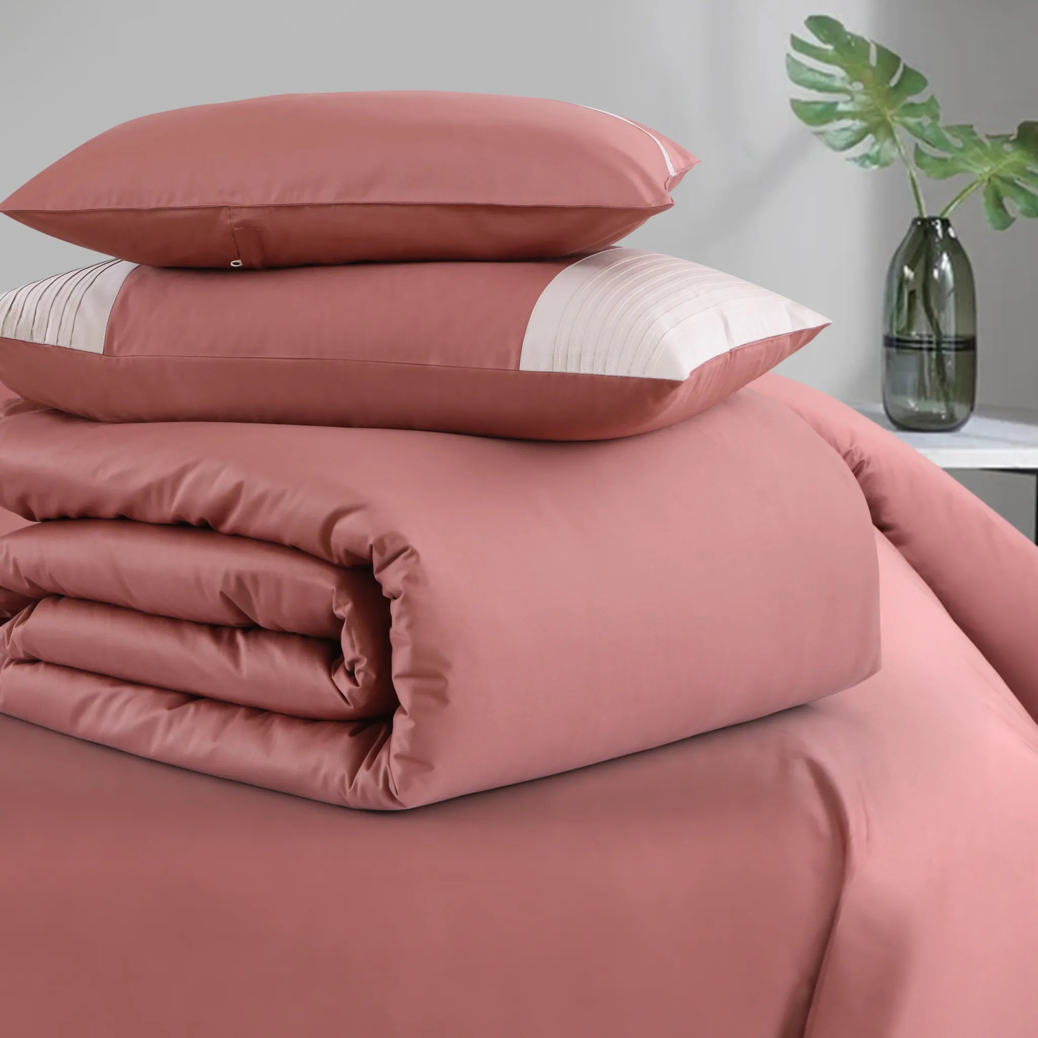 Pink bedding set with pillows on a bed in a room setting.