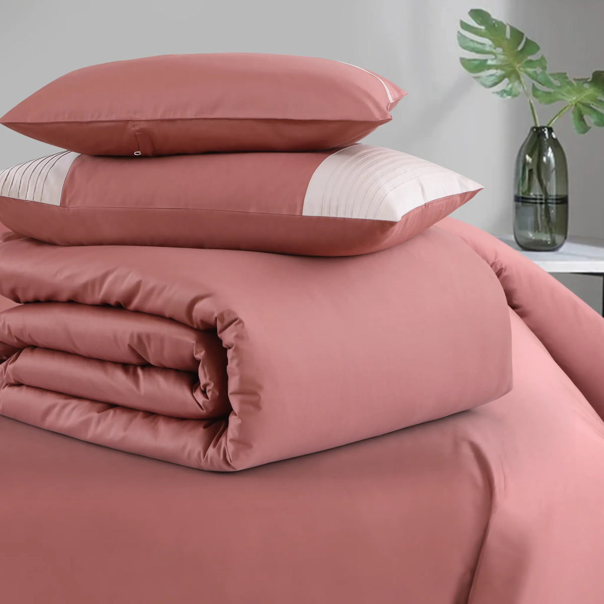 Pink bedding set with pillows on a bed in a room setting.
