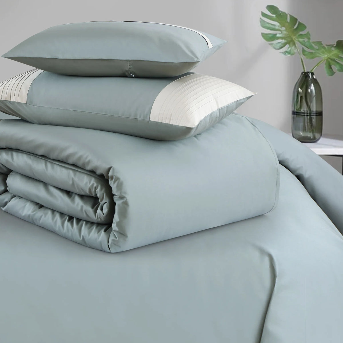 Green bedding set with pillows on a bed in a bedroom setting.