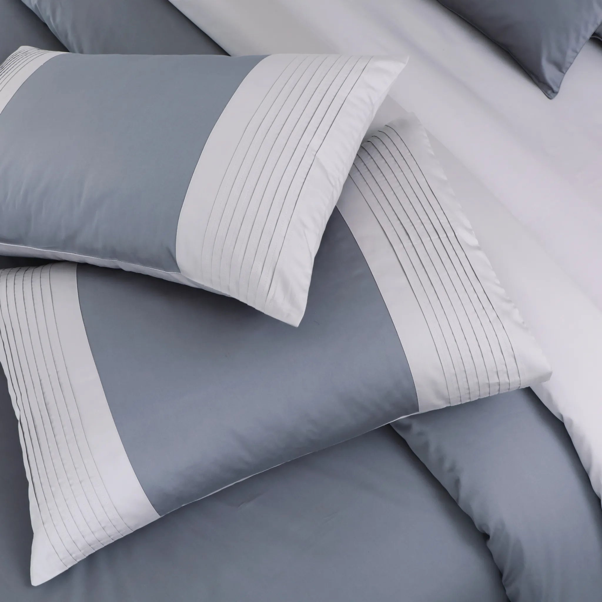 Gray and white bedding set with textured edges on a bed.
