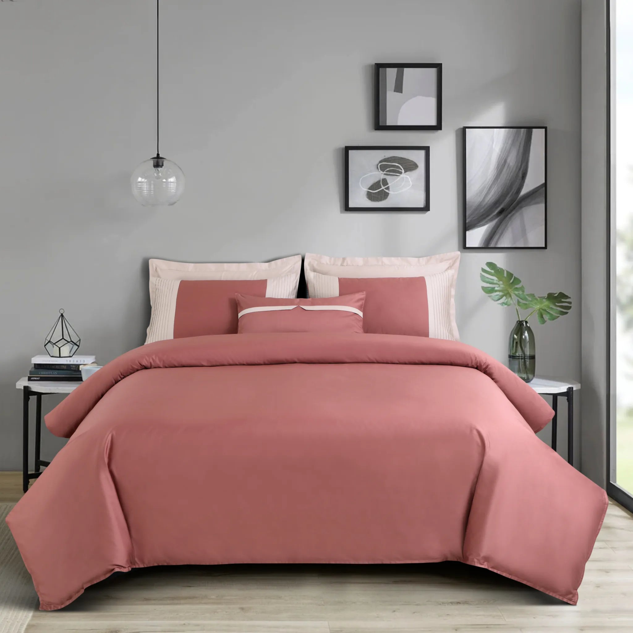 Pink bedding set on a bed in a bedroom with gray walls and framed art.