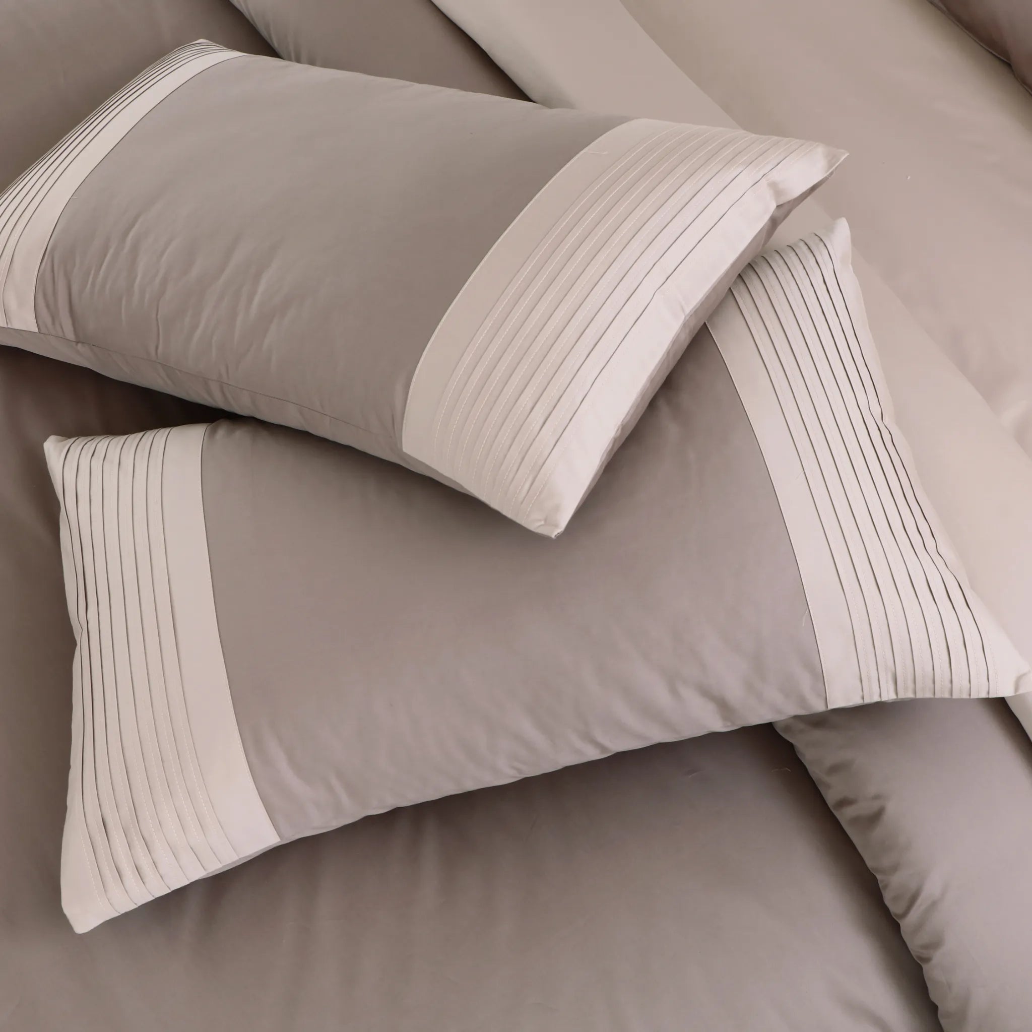 Taupe bedding set with textured pillows on a bed.