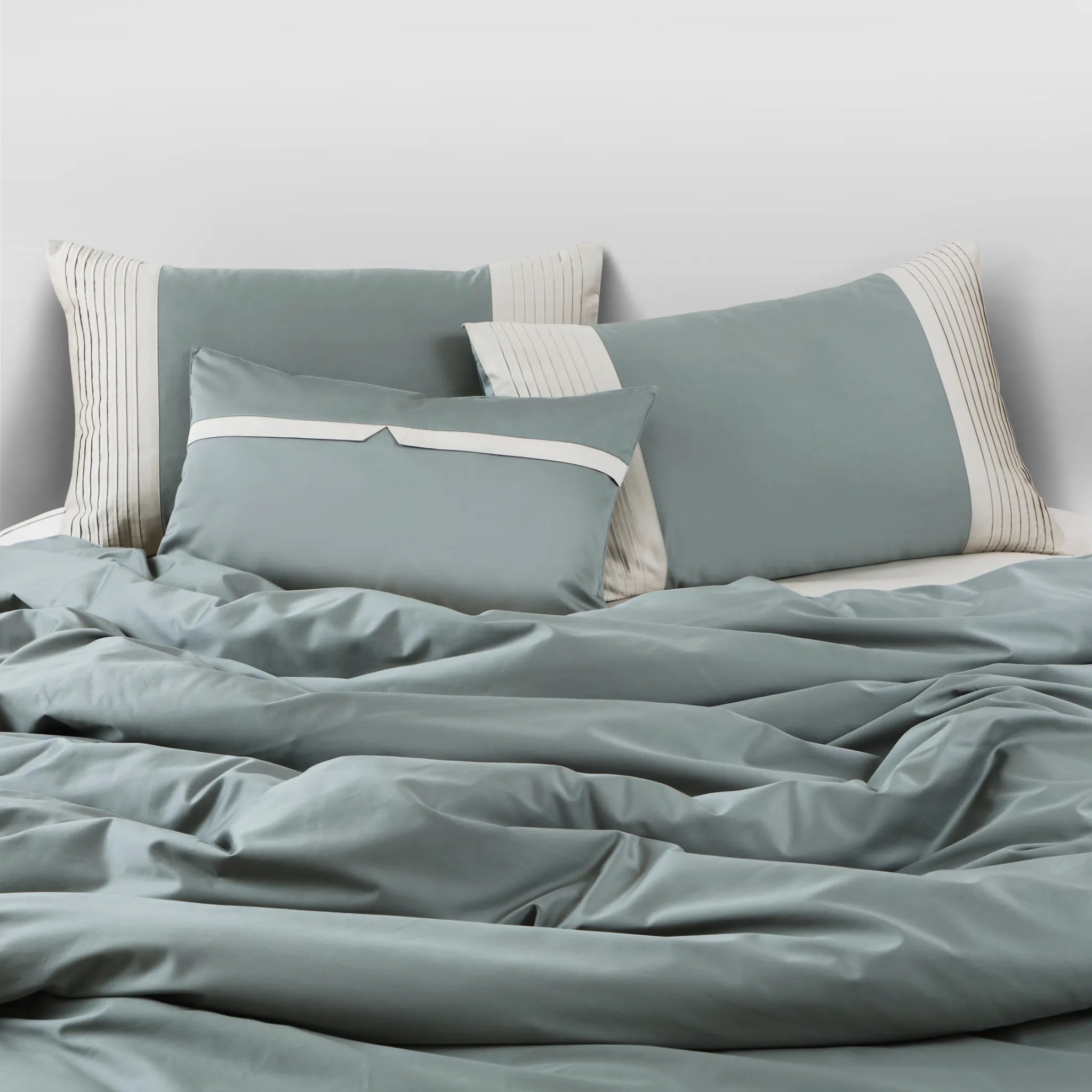 Teal bedding set with matching pillows on a bed against a light gray wall.